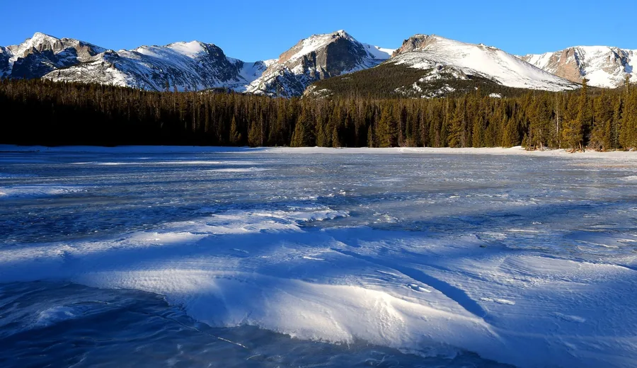 A frozen lake under snow with mountains in the distance